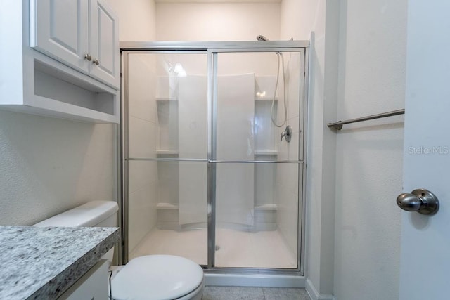 bathroom featuring vanity, toilet, tile patterned floors, and an enclosed shower