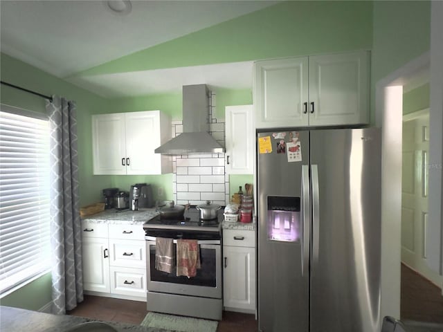 kitchen with lofted ceiling, appliances with stainless steel finishes, white cabinetry, and range hood