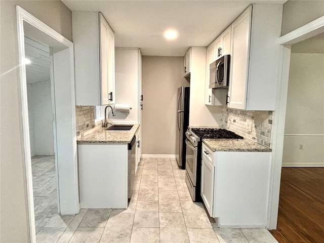 kitchen with light stone counters, stainless steel appliances, sink, and white cabinets