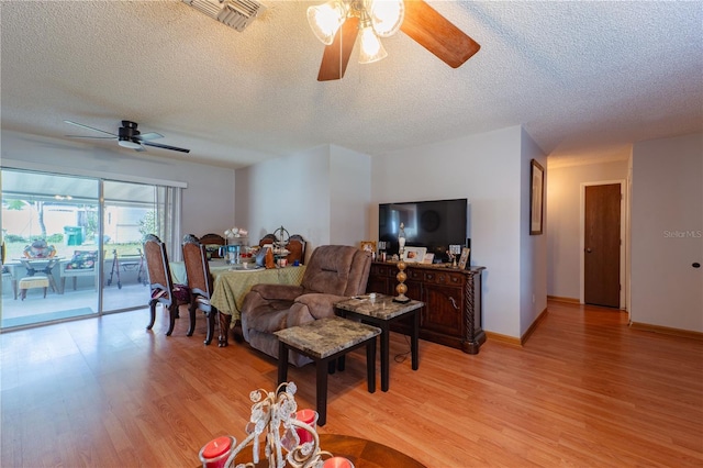 living room featuring light hardwood / wood-style flooring, a textured ceiling, and ceiling fan