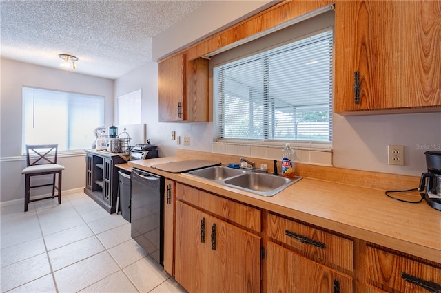 kitchen featuring black dishwasher, light tile patterned flooring, sink, and a wealth of natural light