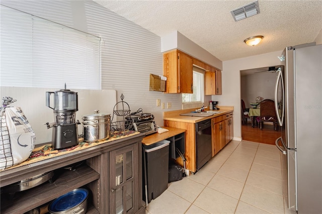 kitchen featuring black dishwasher, sink, a textured ceiling, ceiling fan, and stainless steel refrigerator