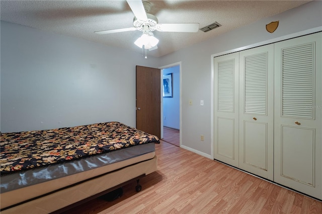 bedroom featuring a closet, a textured ceiling, light wood-type flooring, and ceiling fan