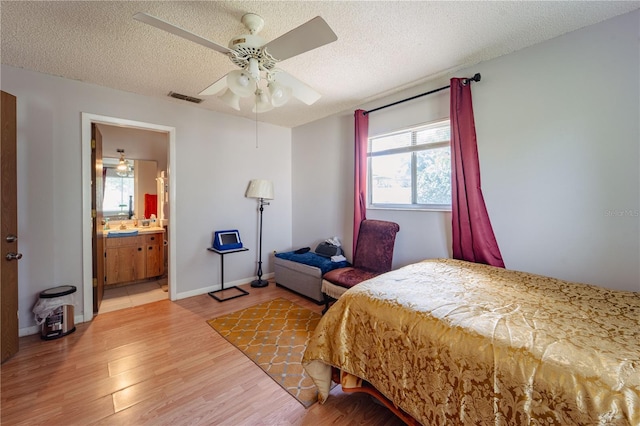 bedroom with hardwood / wood-style floors, a textured ceiling, connected bathroom, and ceiling fan