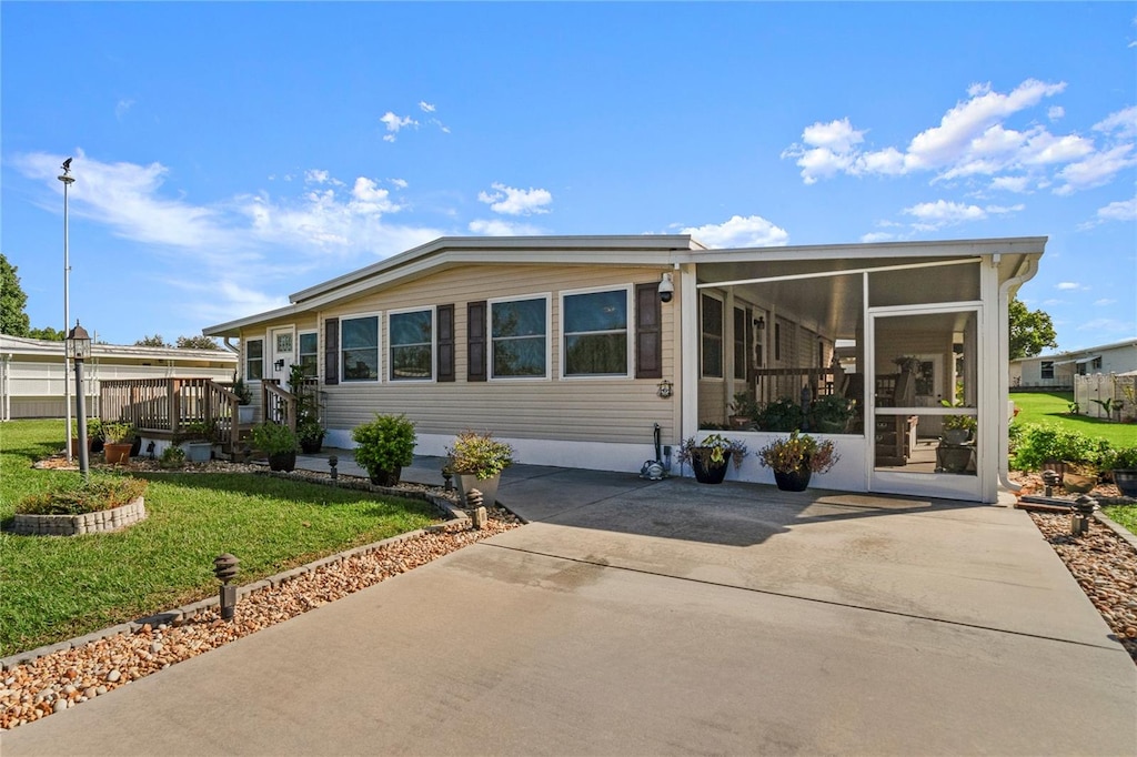 manufactured / mobile home featuring a front yard, a patio, and a sunroom