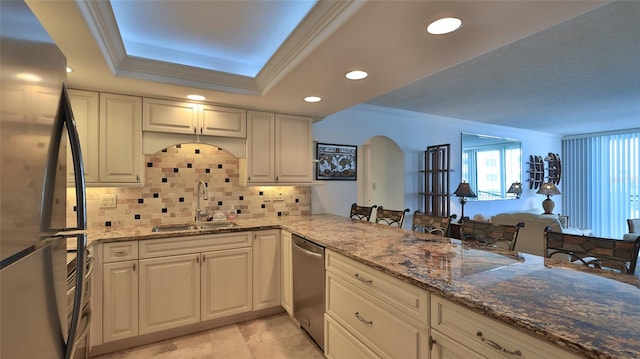 kitchen featuring stone counters, appliances with stainless steel finishes, sink, backsplash, and kitchen peninsula