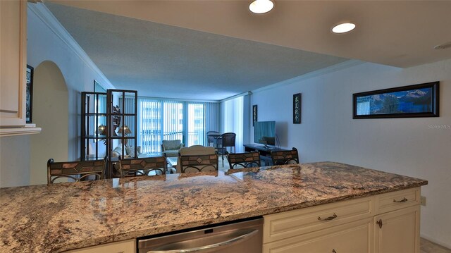 kitchen with white cabinetry, light stone countertops, ornamental molding, and stainless steel dishwasher