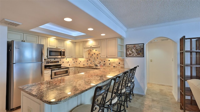 kitchen with crown molding, appliances with stainless steel finishes, sink, and a breakfast bar area