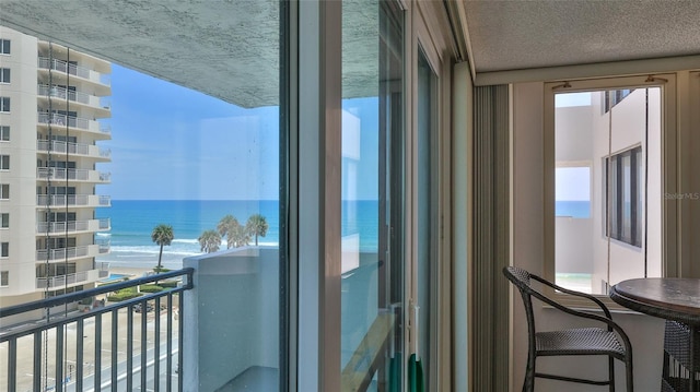 balcony featuring a water view and a beach view