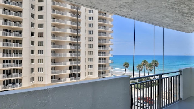 balcony featuring a view of the beach and a water view