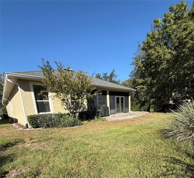 back of house with a lawn and a sunroom