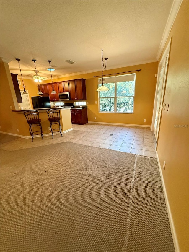kitchen featuring black fridge, ornamental molding, a textured ceiling, pendant lighting, and light colored carpet