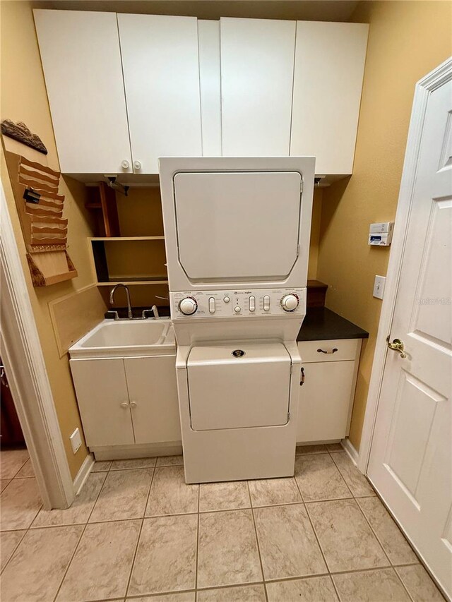 washroom with stacked washer / drying machine, cabinets, and light tile patterned floors