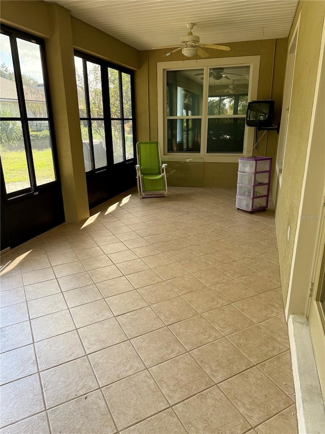 unfurnished sunroom featuring ceiling fan