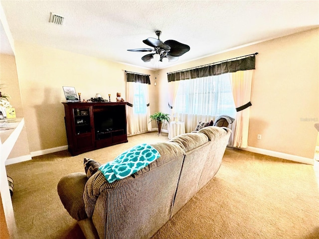 living room featuring a textured ceiling, light colored carpet, and ceiling fan