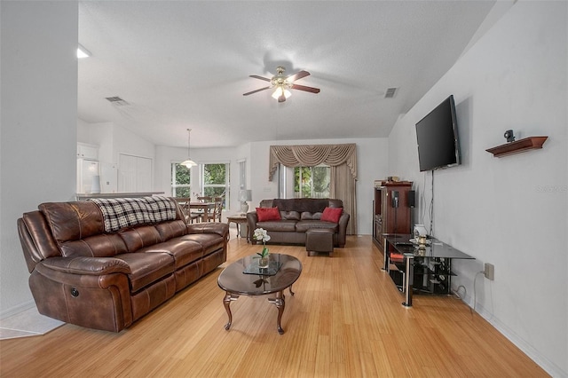 living room featuring light hardwood / wood-style floors, a textured ceiling, and ceiling fan