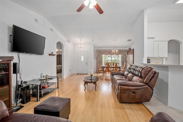 living room with light hardwood / wood-style floors, ceiling fan with notable chandelier, and vaulted ceiling