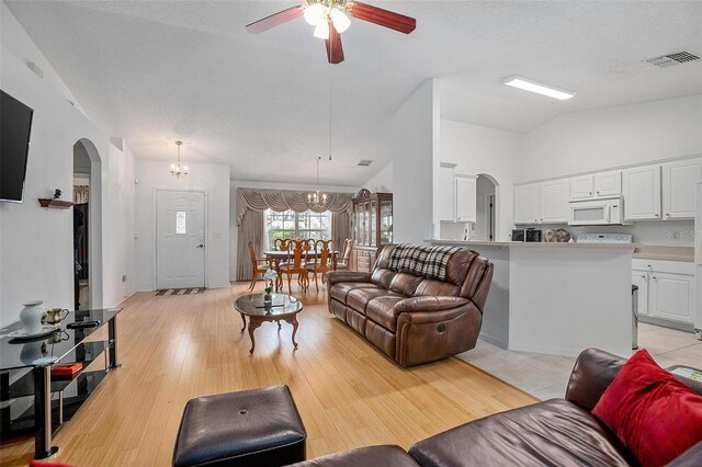 living room with lofted ceiling, a textured ceiling, ceiling fan with notable chandelier, and light hardwood / wood-style floors