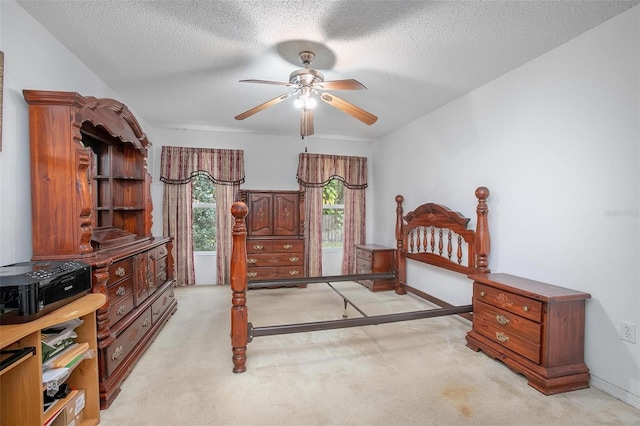 bedroom with a textured ceiling, light colored carpet, and ceiling fan