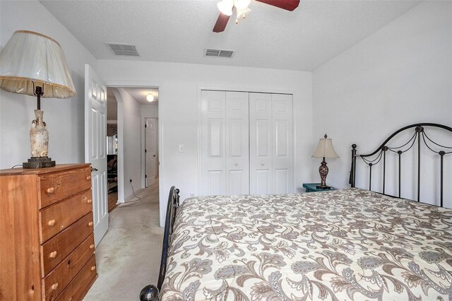 carpeted bedroom with a closet, ceiling fan, and a textured ceiling