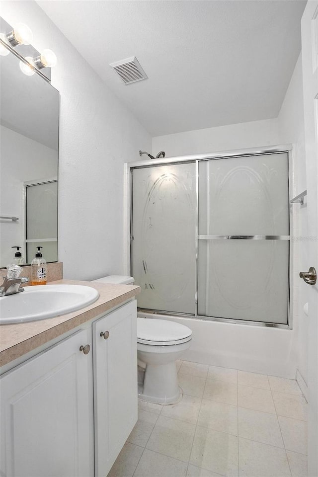 full bathroom featuring vanity, combined bath / shower with glass door, toilet, and tile patterned flooring