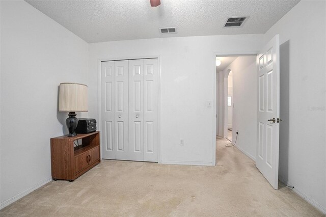 carpeted bedroom with a closet, a textured ceiling, and ceiling fan