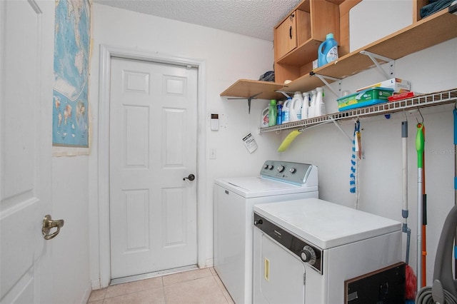 laundry room with a textured ceiling, washing machine and dryer, and light tile patterned floors