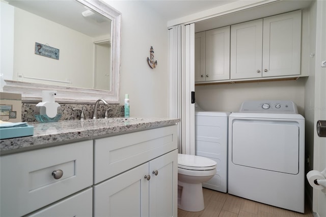 bathroom with vanity, independent washer and dryer, wood-type flooring, and toilet