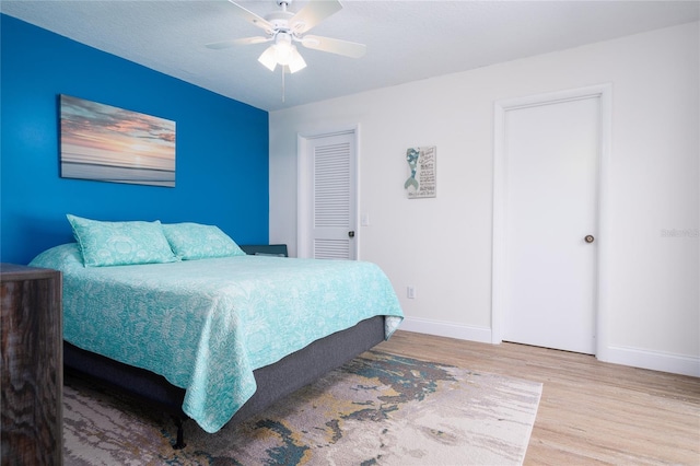 bedroom with a closet, light hardwood / wood-style floors, and ceiling fan