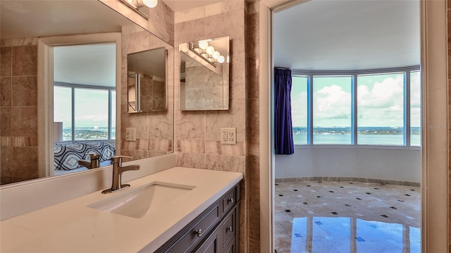 bathroom with plenty of natural light, a water view, tile walls, and vanity