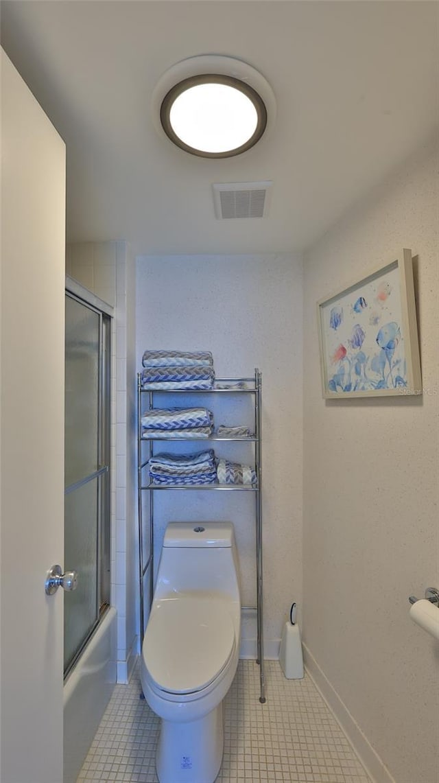 bathroom featuring shower / bath combination with glass door, tile patterned flooring, and toilet