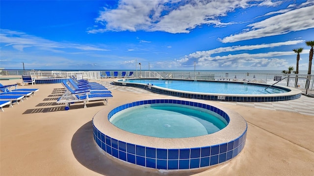 view of pool with a water view, a hot tub, and a patio area