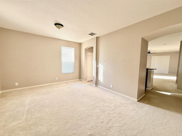 empty room with ceiling fan, a textured ceiling, and light colored carpet