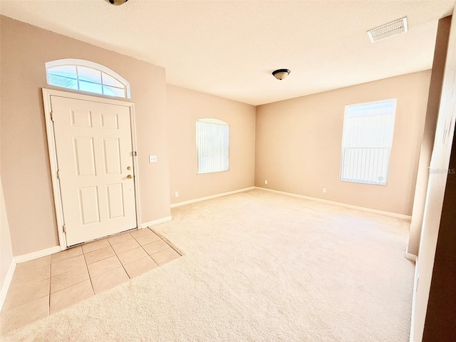 entrance foyer featuring a textured ceiling and light colored carpet