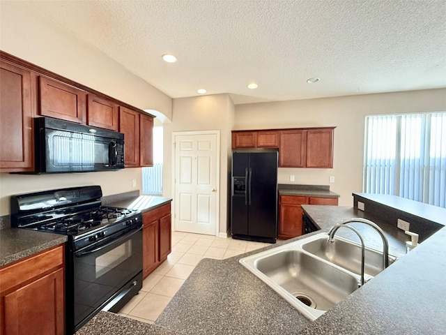 kitchen featuring a textured ceiling, black appliances, sink, and light tile patterned floors