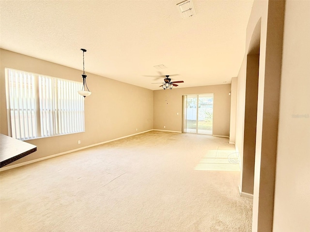 empty room featuring a textured ceiling, carpet, and ceiling fan