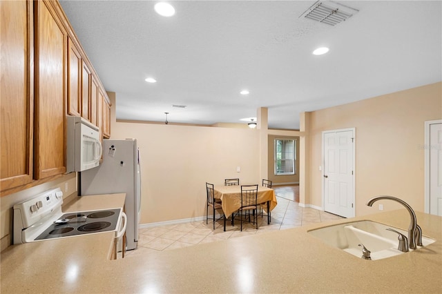 kitchen with sink, light tile patterned floors, and white appliances