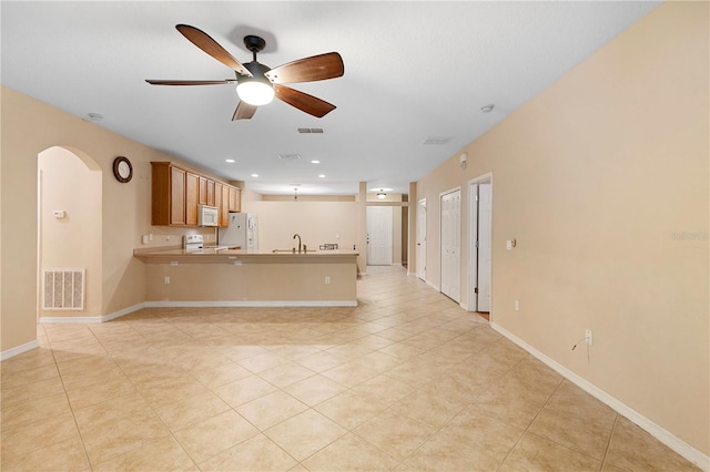 kitchen featuring kitchen peninsula, sink, light tile patterned flooring, white appliances, and ceiling fan