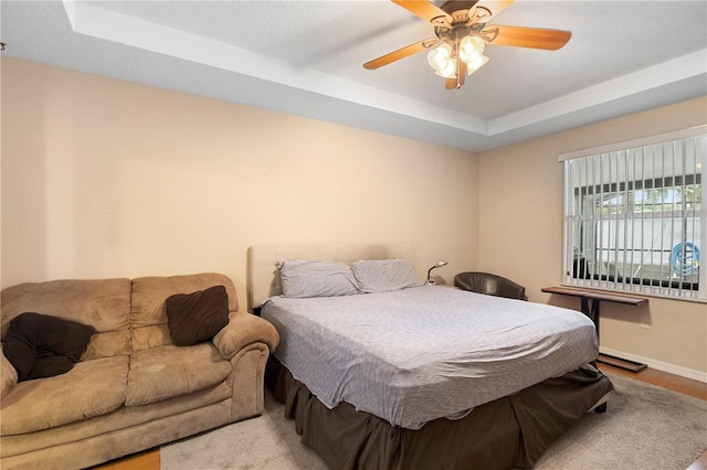 bedroom featuring light hardwood / wood-style floors, a tray ceiling, and ceiling fan