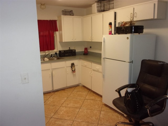 kitchen featuring sink, white cabinetry, white fridge, and light tile patterned flooring