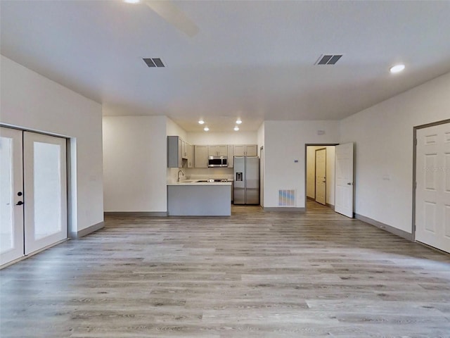 unfurnished living room featuring french doors, light hardwood / wood-style flooring, and sink