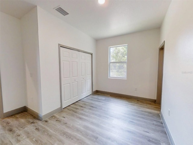 unfurnished bedroom with light hardwood / wood-style flooring and a closet