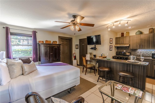 bedroom with ceiling fan, a textured ceiling, and light tile patterned floors