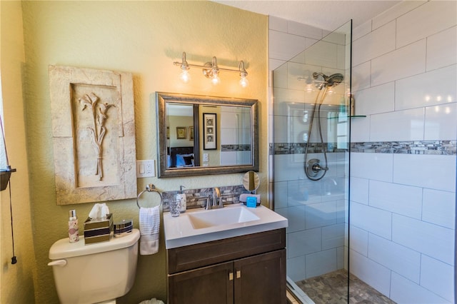 bathroom with a tile shower, toilet, and vanity