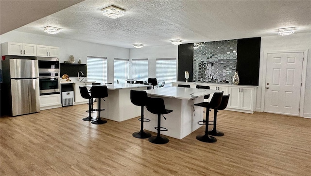 kitchen featuring appliances with stainless steel finishes, a breakfast bar, white cabinets, and a center island