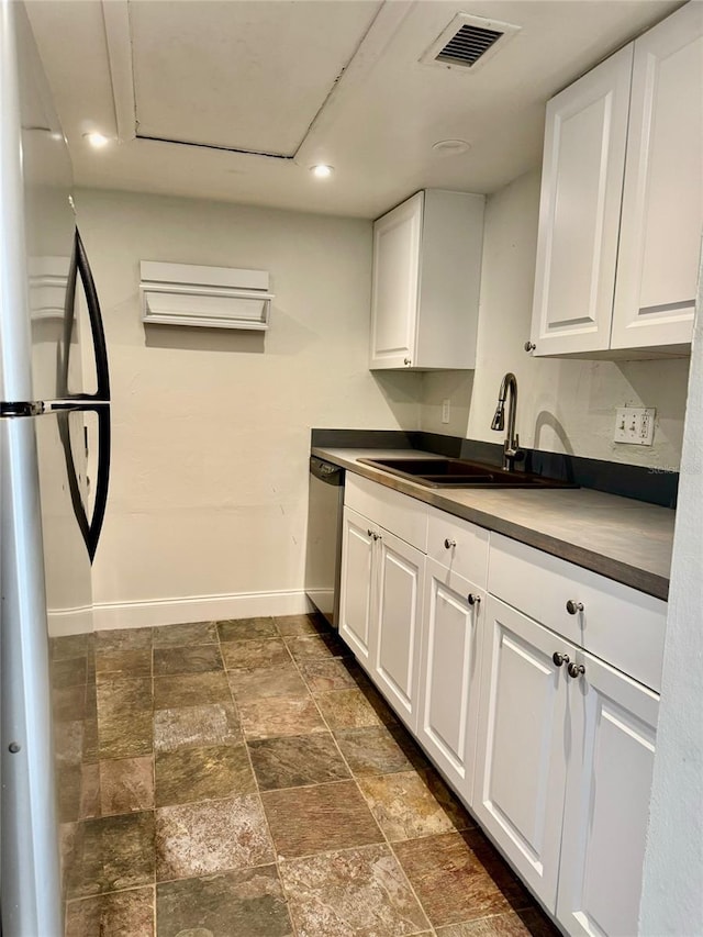 kitchen featuring stainless steel dishwasher, sink, white cabinets, and fridge