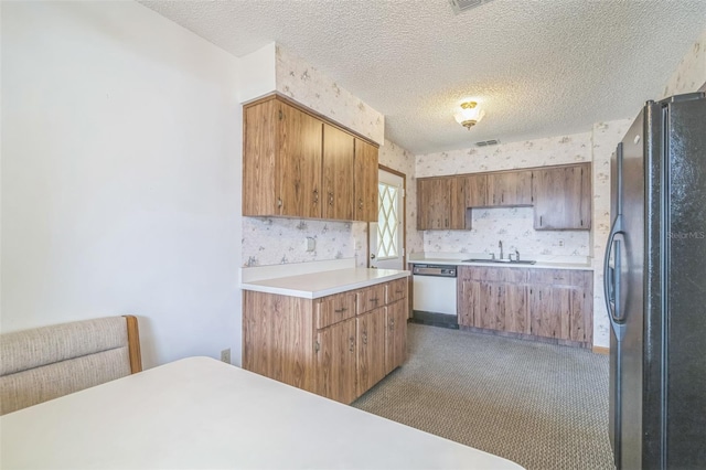 kitchen featuring black refrigerator, a textured ceiling, light colored carpet, and stainless steel dishwasher