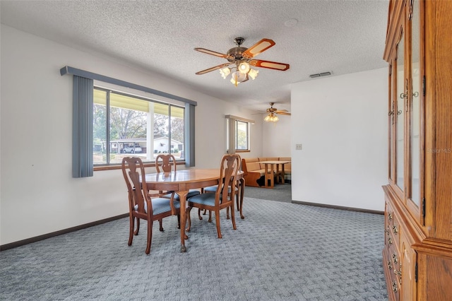 dining space with a textured ceiling, dark carpet, and ceiling fan