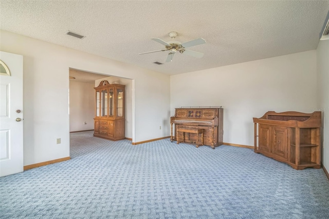 spare room with ceiling fan, light colored carpet, and a textured ceiling