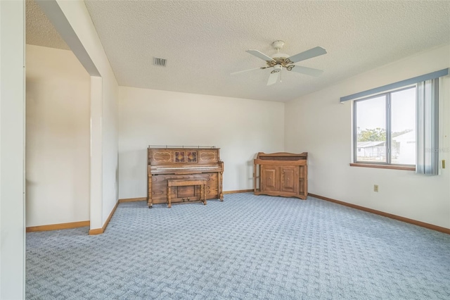 miscellaneous room with ceiling fan, light carpet, and a textured ceiling